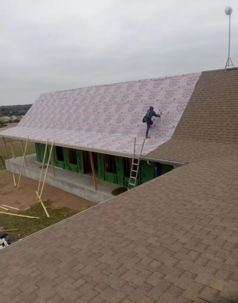 Worker preparing underlayment for a metal roof installation in Hannibal